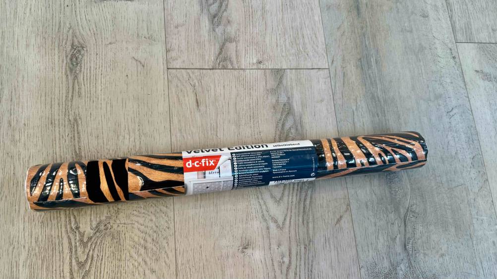 Eine getestete Möbelfolie in Originalverpackung auf einem Holzboden.