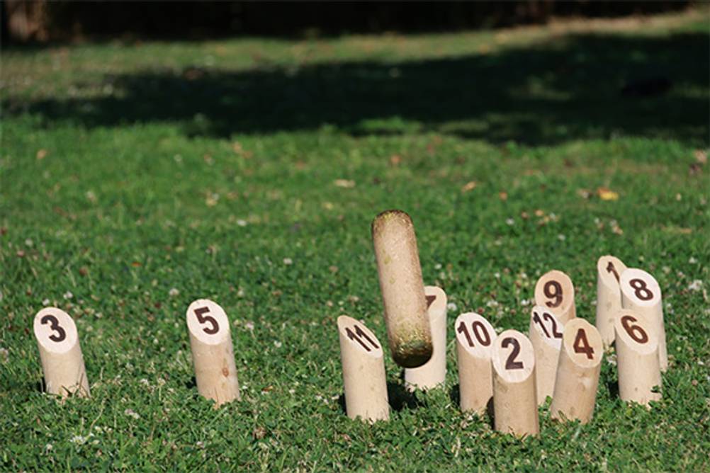 Mölkky im Test: Ein Wurfholz das auf die Pins zufliegt.