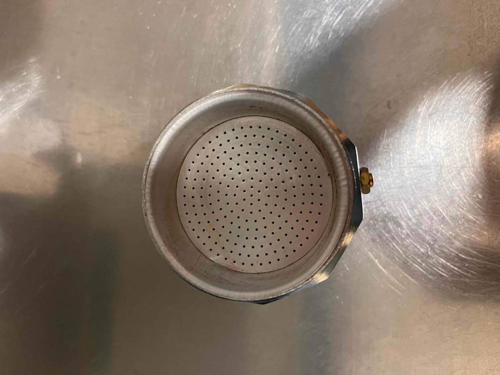 Mokka-Kaffeemaschine im Test: Ansicht von oben eines geöffneten Modells auf einer Aluminiumablage, mit Fokus auf den Kaffee-Sieb-Behälter.