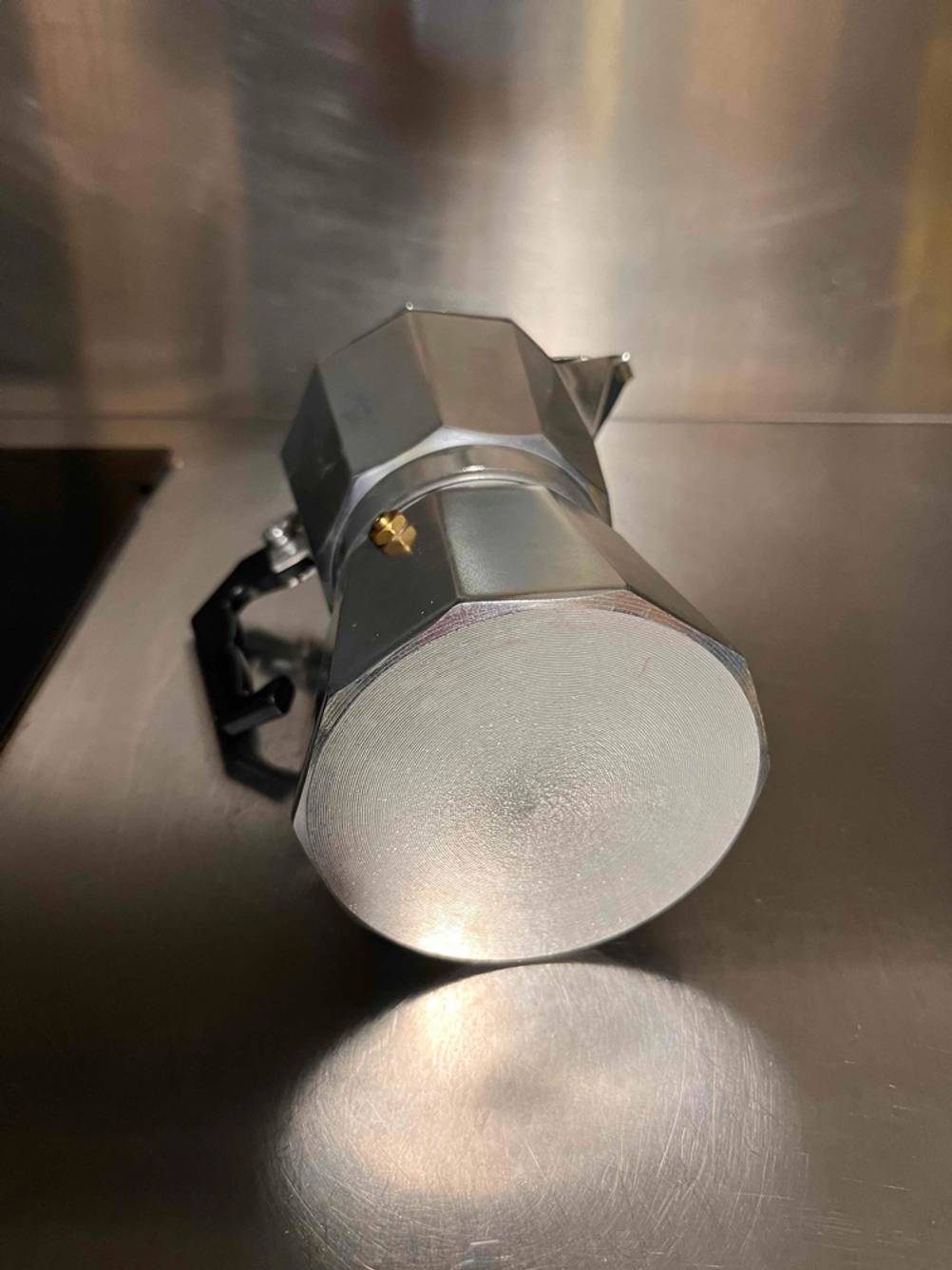Metallfarbene Mokka-Kaffeemaschine im Test liegt mit Blick auf das Boden-Material auf einer Aluminiumablage.