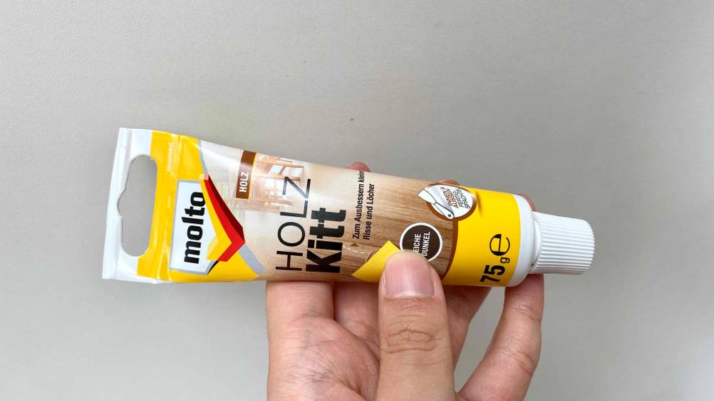 Im Test: Eine Hand hält eine Tube Molto Holzkitt.