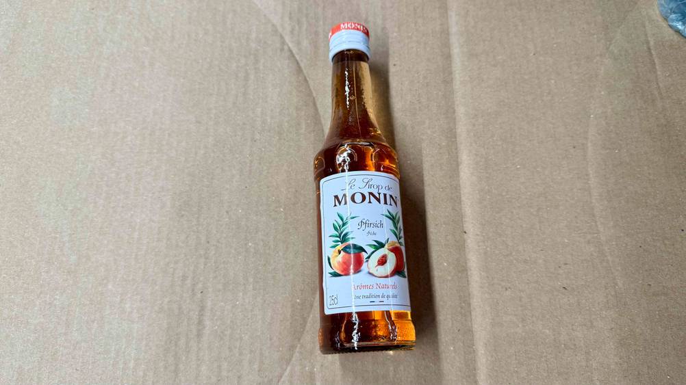 Eine Flasche des getesteten Monin-Sirups auf einem Karton liegend.