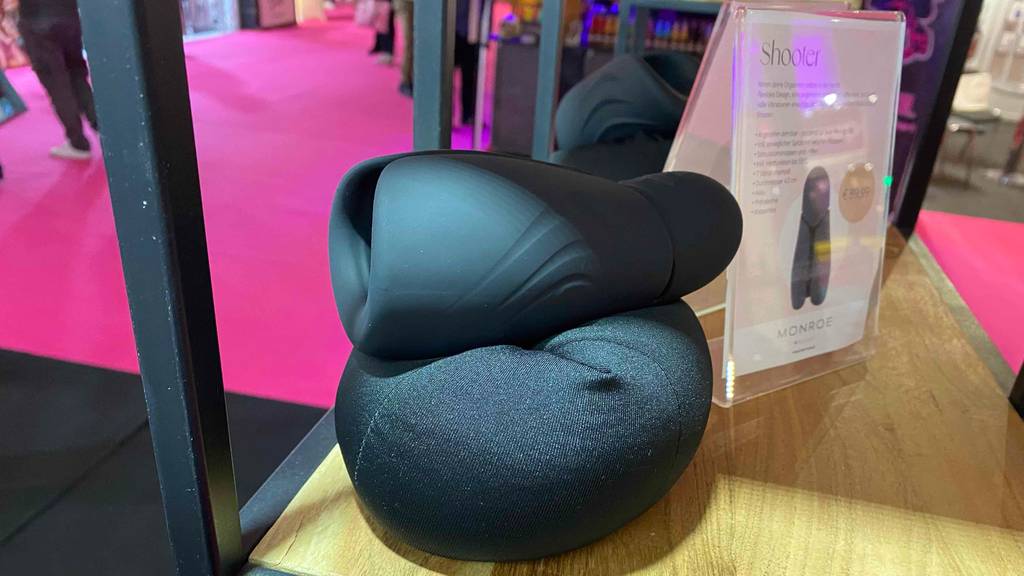 Masturbator-Test: Schwarzer Masturbator Shooter liegt auf einem schwarzen Ausstellungskissen in einem Holzregal.