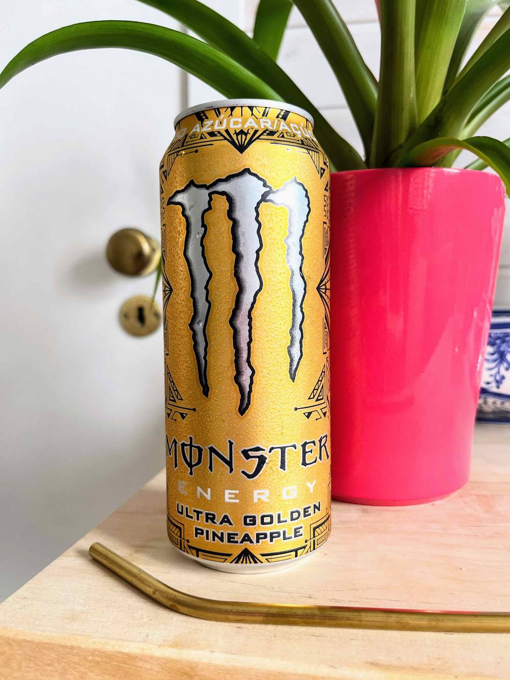Vor eine Dose getesteter Energy-Drink liegt ein goldener Metallstrohhalm.