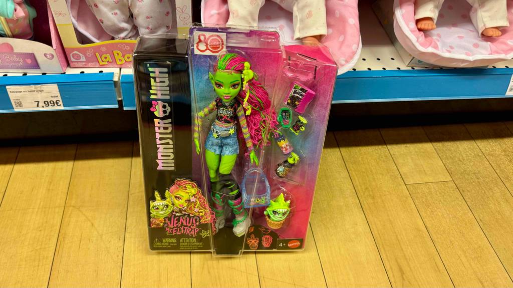 Monster-High-Puppen im Test: Blick von schräg oben auf eine verpackte Puppe, die am Holzboden steht.