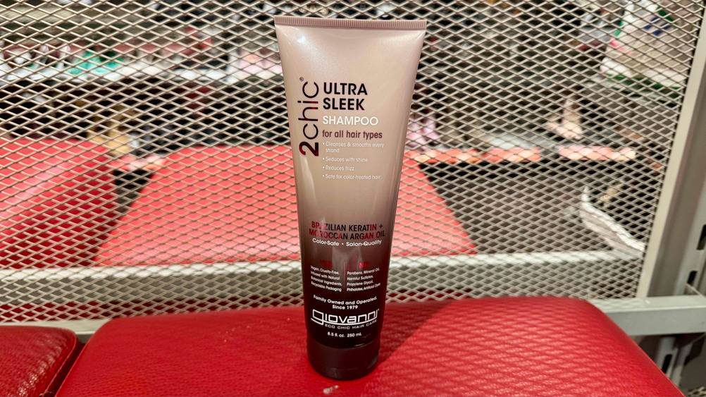 Ein getestetes Moroccanoil-Shampoo auf einer roten Fläche vor einem Gitter.