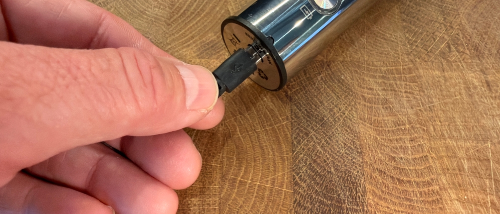Eine Hand steckt das Ladekabel in den Mosuo Mos-Frother-001