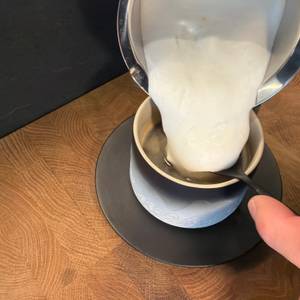 Milchschaum vom Mosuo Mos-Frother-001 wird in eine Tasse mit Kaffee geschüttet