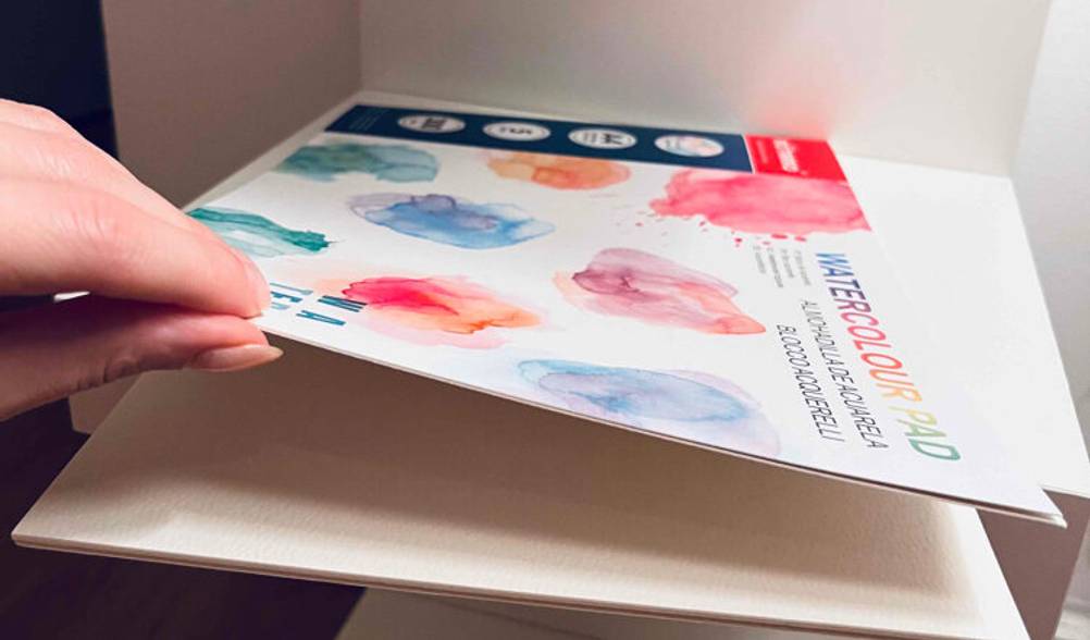 Ein DIN-A4-Block mit Aquarellpapier im Test wird von einer Hand geöffnet.