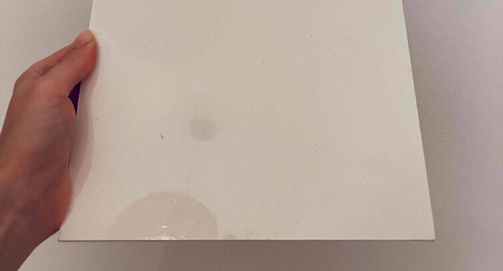 Eine Damenhand hält einen DIN-A4-Block mit getestetem Aquarellpapier vor einer weißen Oberfläche.