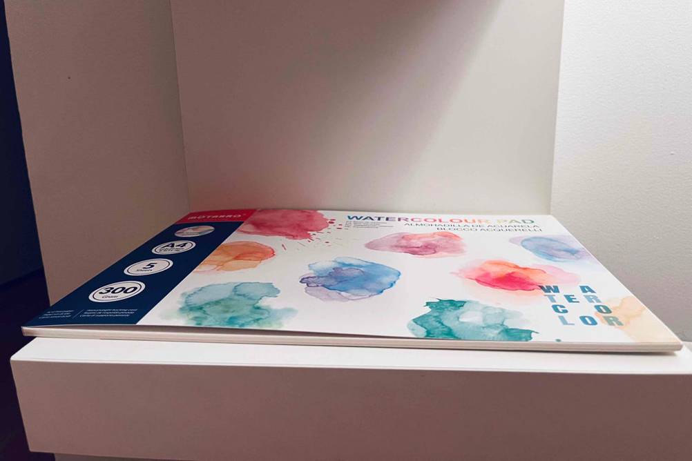 Aquarellpapier-Test: Ein Block mit bunten Aquarelltupfern liegt auf einem Regal.