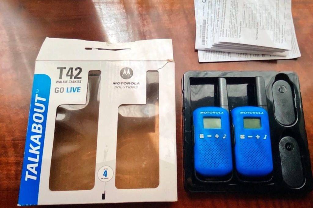 Funkgeräte im Test: Zei blaue Modelle T42 Go Live der Marke Motorola befinden sich neben ihrer Verpackung sowie Bedienungsanleitung auf einem Tisch.