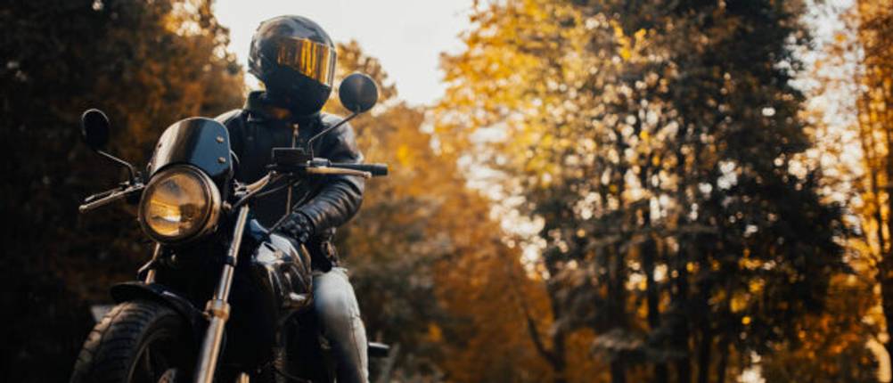 Person sitzt in voller Montur auf einem geparkten Motorrad.