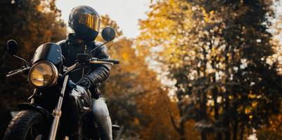 Person sitzt in voller Montur auf einem geparkten Motorrad.