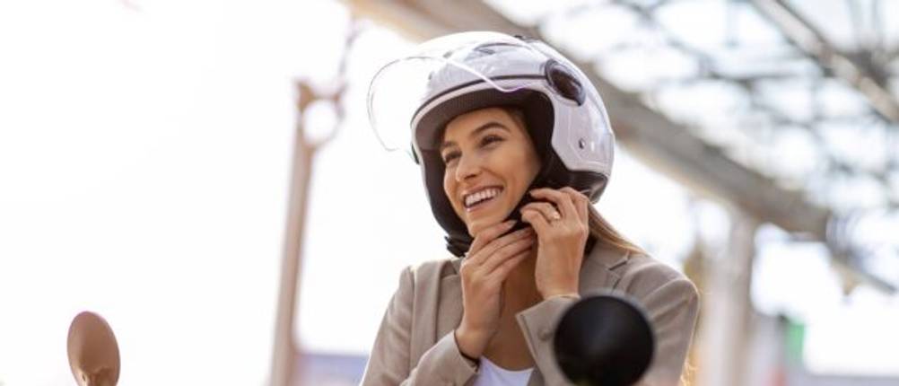 Frau auf einem Motorrad schließt den Helm.