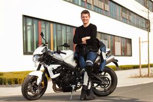 Motorradversicherung-Test: Ein junger Mann steht in Schutzkleidung vor seinem Motorrad.