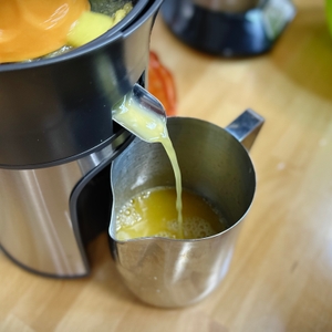 Frisch gepresster Orangensaft fließt aus dem Ausguss der Moulinex PC603D10 in eine Edelstahlkanne.
