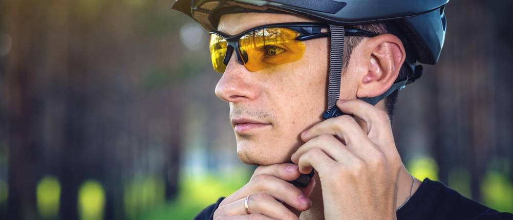 Mountainbike-Helm Herren getestet: Ein Mann schließt seinen Helm mit Riemen.