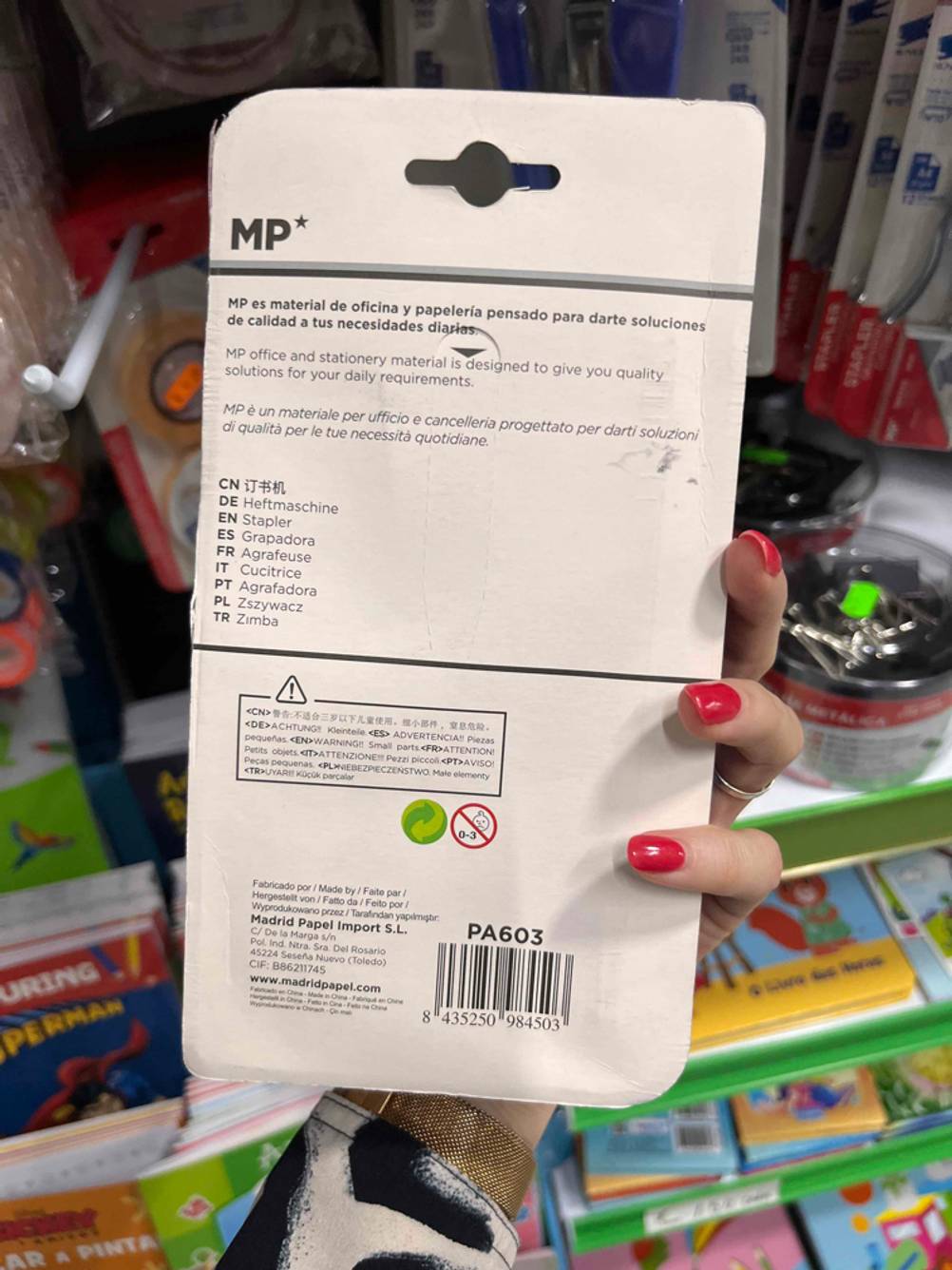 Tacker im Test: Hand hält Originalverpackung mit Fokus auf die Rückseite inklusive Produktbeschreibung in einem Einkaufsbereich.