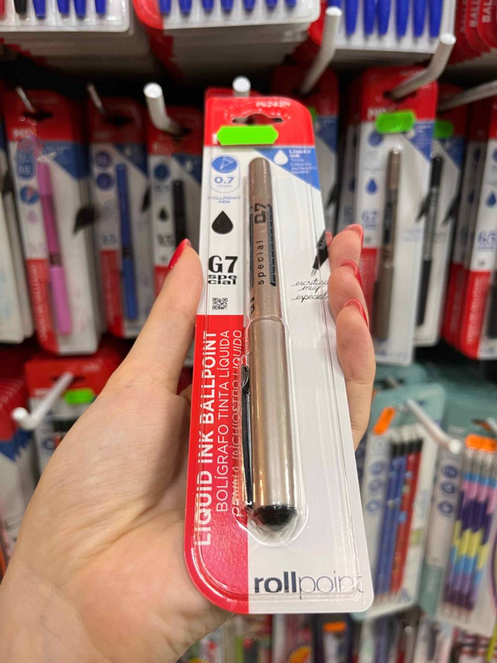 Tintenroller getestet: Nahaufnahme der Kappe eines verpackten Tintenrollers der von einer Hand vor ein Regal gehalten wird.