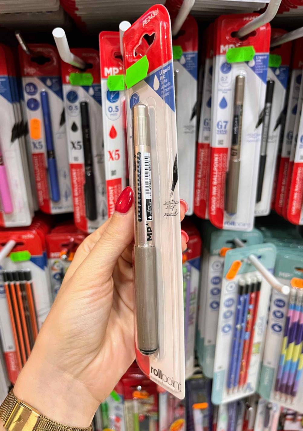Getestet: Eine Hand hält einen verpackten Tintenroller seitlich vor ein Regal.