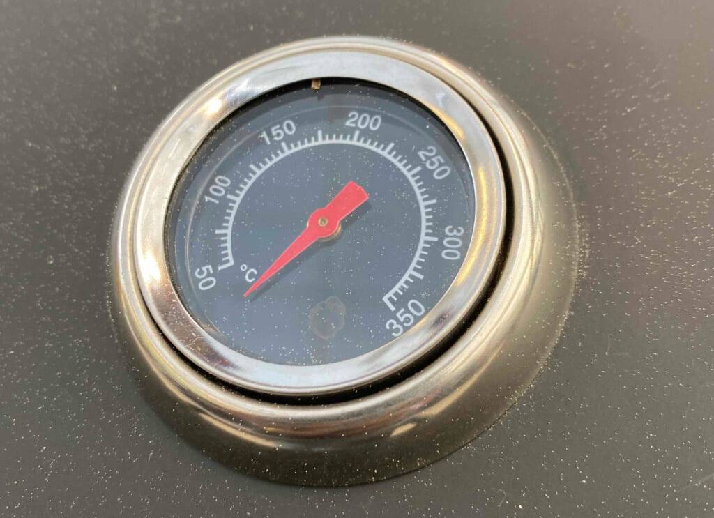 Balkon-Gasgrill im Test: Detailansicht eines auf anthrazitfarbenem Metall integrierten, runden Thermometers von 50 bis 350 Grad Celsius.