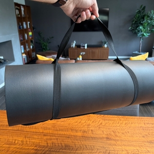 Eine Hand hebt die Msports-Gymnastikmatte Premium am Tragegurt hoch