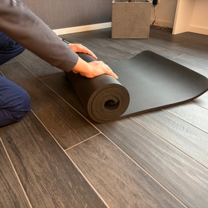 Eine Person rollt die Msports-Gymnastikmatte Premium zusammen