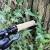 Ein beiger MTB-Griff der Marke FIFTY-FIFTY, montiert an einem schwarzen Lenker, lehnt an einem Baum mit Efeu. Der Hintergrund zeigt Naturdetails.