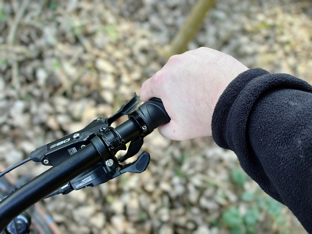 Eine Hand umschließt die ergonomisch geformten Reetee-Fahrradgriffe während der Fahrt auf einem Mountainbike.