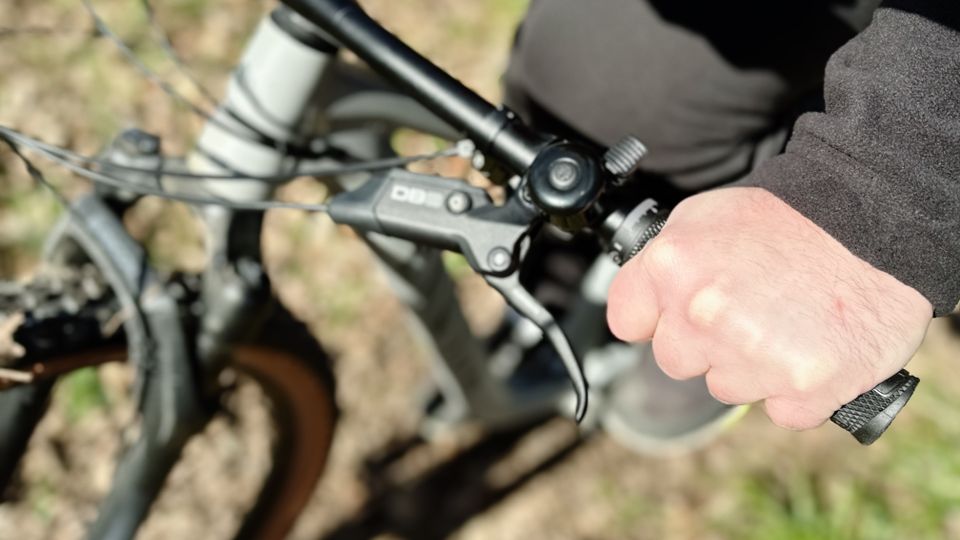 Eine Hand greift den SQlab 7OX Griff am Lenker eines Mountainbikes im Outdoor-Einsatz. Die strukturierte Oberfläche sorgt für Halt.