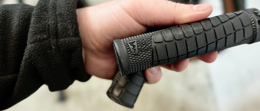 Eine Hand hält die SQlab 7OX MTB-Griffe, die mit einer seitlichen Markierung zur richtigen Montage gekennzeichnet sind.