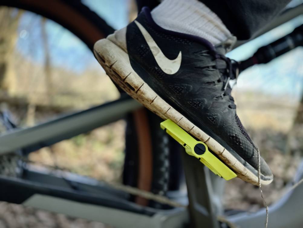Seitliche Ansicht eines Crankbrothers Stamp 1 Pedals mit einem Sportschuh auf der Plattform. Die Fußhaltung zeigt eine stabile Position beim Treten.