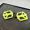 Zwei Crankbrothers Stamp 1 Pedale in leuchtendem Gelb liegen nebeneinander auf einer Werkbank. Die Pins sind bereits vormontiert.