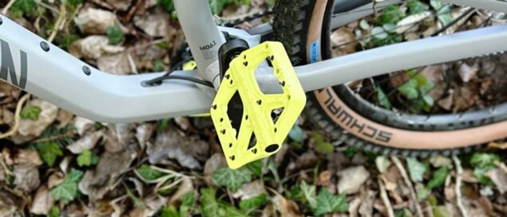 Ein Crankbrothers Stamp 1 Pedal montiert an einem Canyon-MTB. Das gelbe Pedal bildet einen Kontrast zum grauen Rahmen des Fahrrads.
