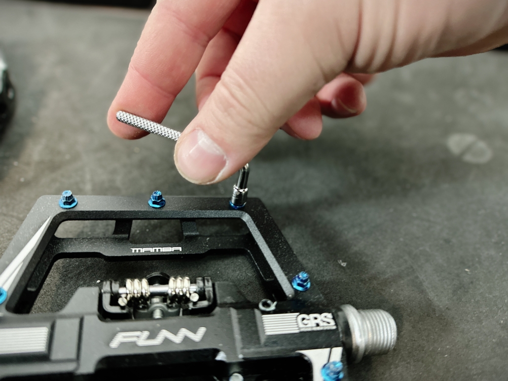 Eine Hand entfernt mit einem Werkzeug einen Pin aus dem Funn-Mamba-Pedal. Die Pins sind austauschbar und individuell anpassbar.