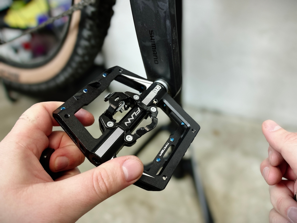 Eine Hand hält das Funn Mamba Pedal mit sichtbar integriertem SPD-Klicksystem. Die Kombination aus Klick- und Plattformseite sorgt für hohe Vielseitigkeit.