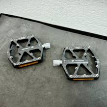 Zwei Gewage USGE323 Pedale liegen auf einer Werkbank. Die CNC-gefrästen Kanten und die seitlichen Reflektoren sind gut sichtbar.
