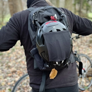 Ein Mann trägt den MTB-Rucksack von Evoc mit Helmhalterung auf dem Rücken.