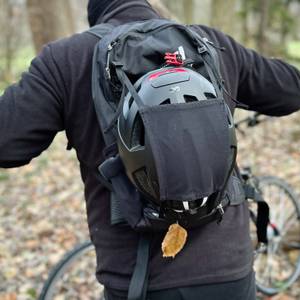 Ein Mann trägt den MTB-Rucksack von Evoc mit Helmhalterung auf dem Rücken.