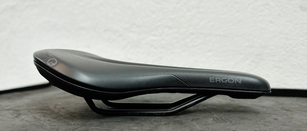 Seitliche Nahaufnahme des Ergon SMC Core MTB-Sattels. Die schwarze Oberfläche mit dem Ergon-Logo und das geschwungene Design sind deutlich sichtbar.