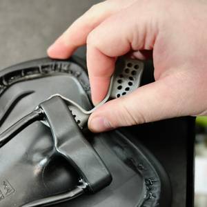 Eine Hand entfernt den Elastomer-Dämpfer aus der Active-Federung des SQlab 610 M-D Active Sattels. Die Lochstruktur des Elastomers ist gut sichtbar.