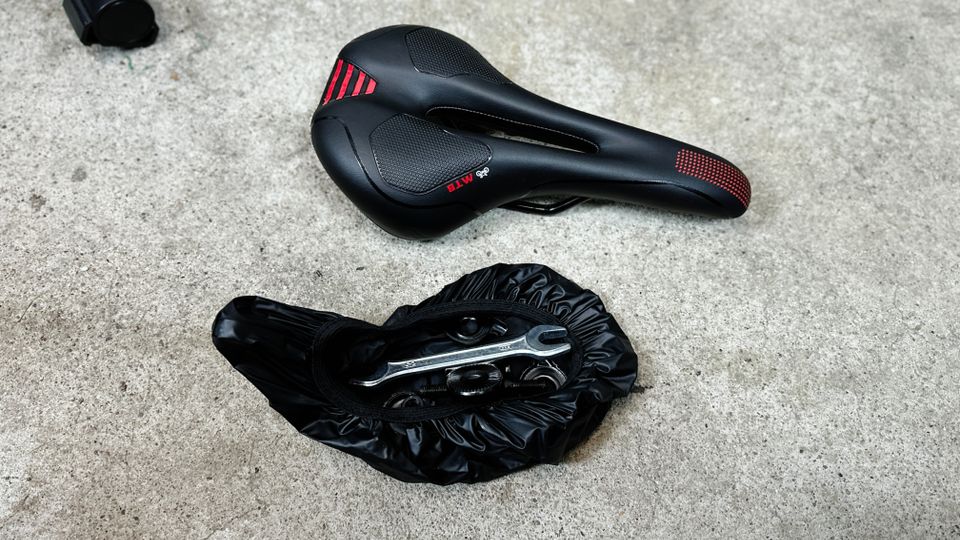 Der Regenschutz des Youngdo MTB-Sattels wird als praktische Tasche für Zubehör und Werkzeug genutzt.