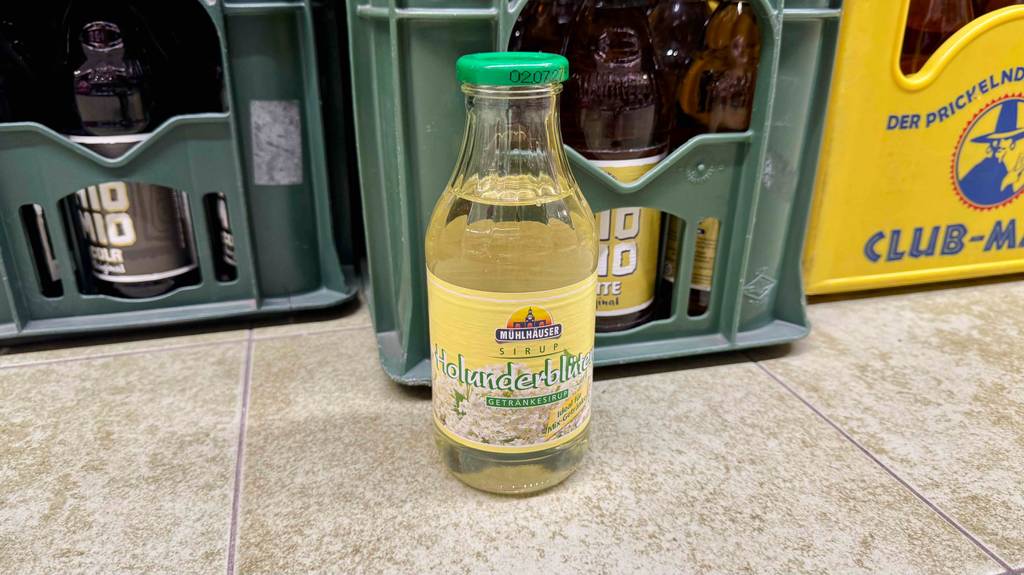 Eine Flasche Getränkesirup steht zum testen vor Getränkekisten.