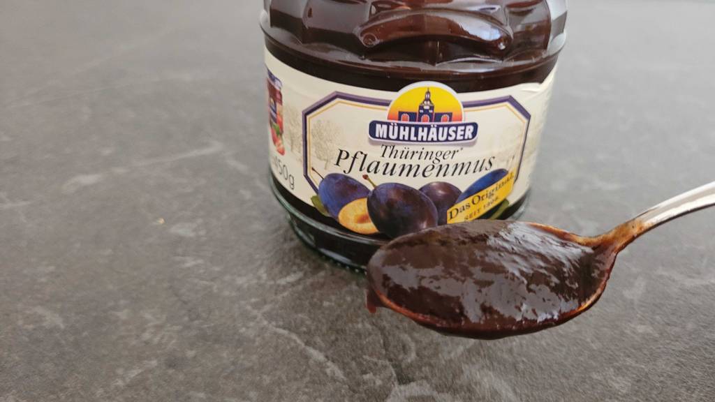 Pflaumenmus im Test auf einem Teelöffel vor einem Glas mit Mühlhäuser Pflaumenmus.