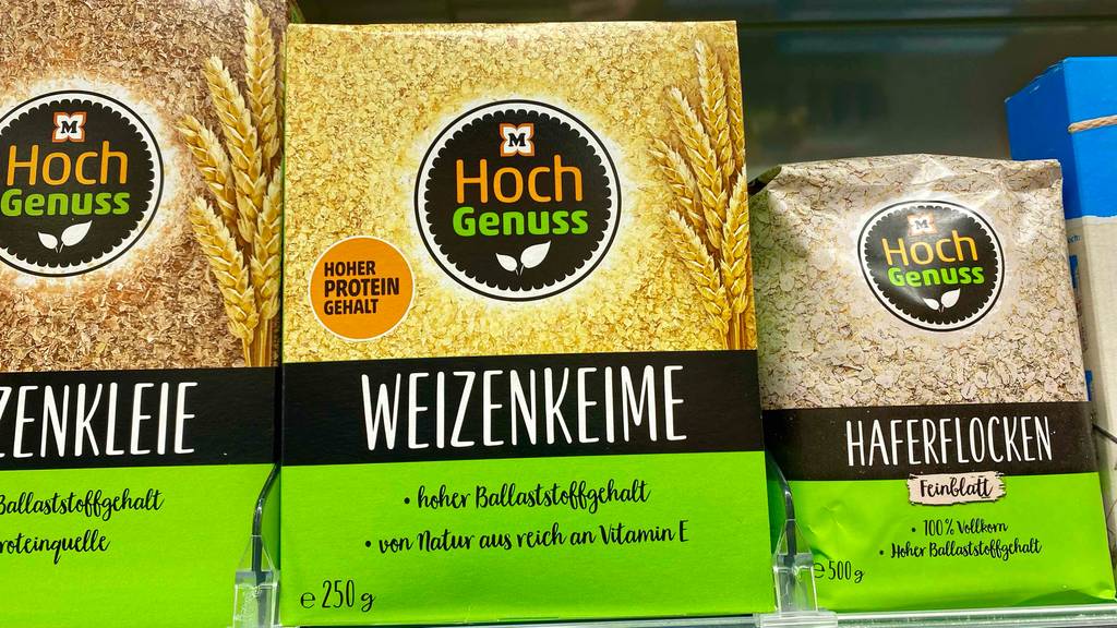 In einem Verkaufsregal stehen neben einer gelb-schwarz-grünen Verpackung mit Müller Weizenkeime im Test Weizenkleie und Haferflocken.