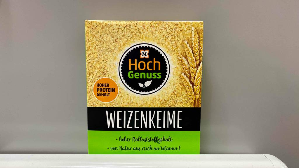 Müller Hoch Genuss Weizenkeime im Test befinden sich in ihrer gelb-schwarz-grünen Verpackung vor einem grauen Hintergrund.