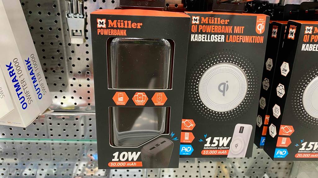 Im Test: Powerbanks mit 30.000 mAh Kapazität der Marke Müller hängen in ihren schwarz-orangen Verpackungen an einem Verkaufsregal.
