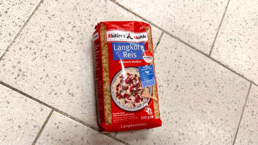 Eine Packung getesteter Langkornreis liegt auf Fliesen.