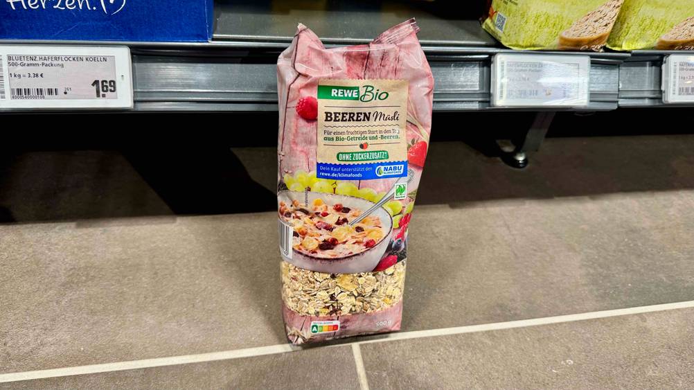 Eine Packung des getesteten Müsli ohne Zuckerzusatz steht vor einem Regal auf dem Boden.